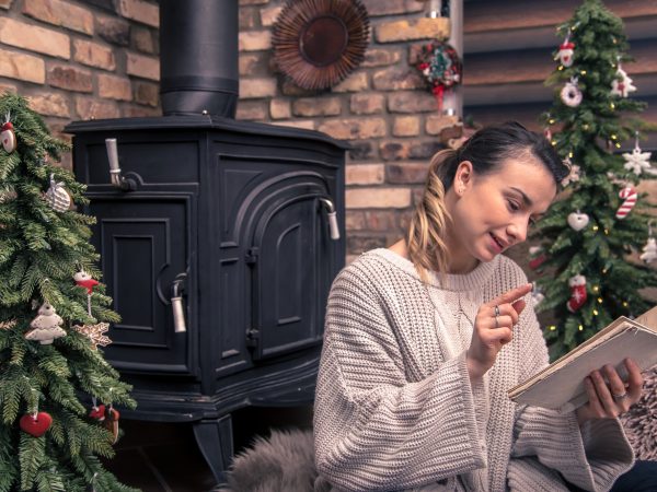 girl reading a book in a cozy home atmosphere near the fireplace