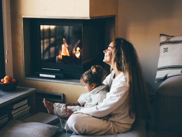Happy mom and daughter resting near fireplace at home.